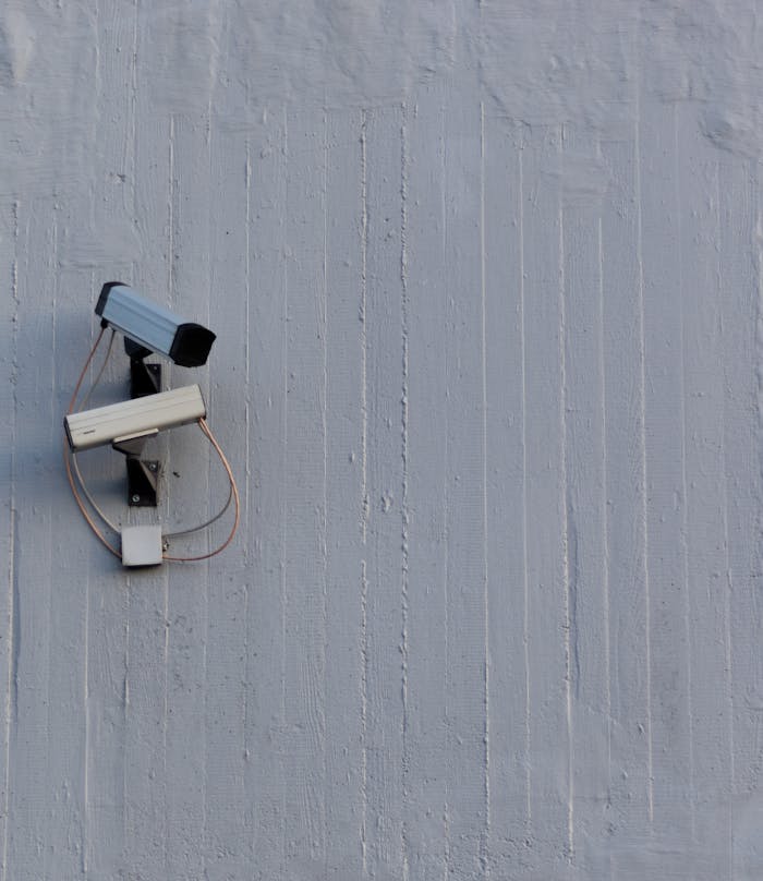 Two surveillance cameras mounted on a wall for security and safety monitoring.